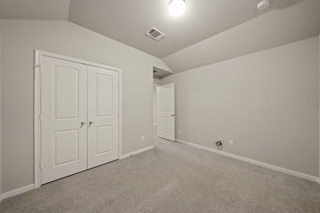 unfurnished bedroom featuring light carpet, a closet, and vaulted ceiling