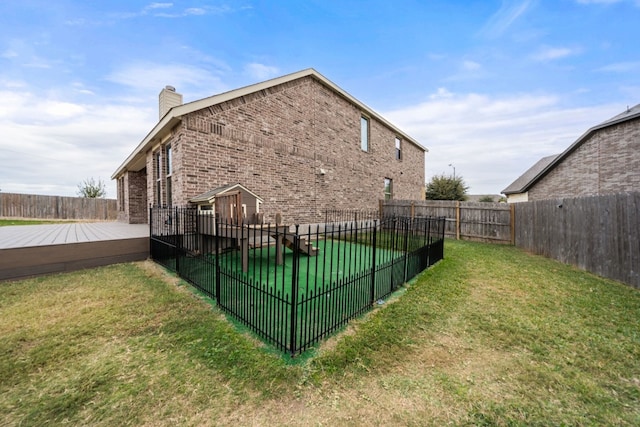 rear view of house featuring a lawn and a deck