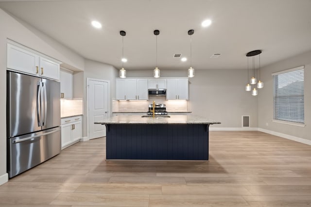 kitchen featuring stainless steel appliances, white cabinetry, and an island with sink