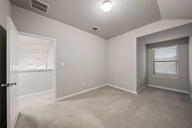 spare room featuring light colored carpet and lofted ceiling