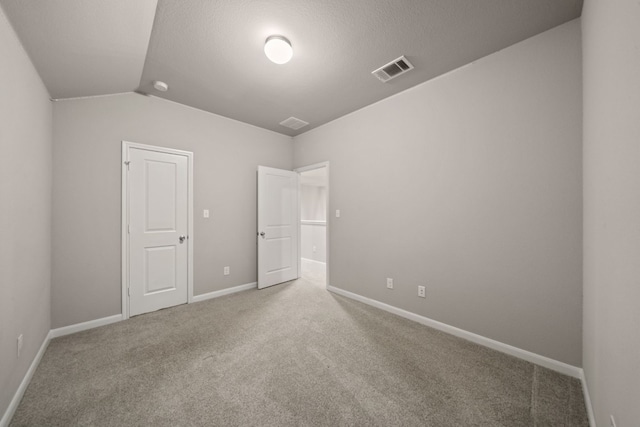 unfurnished bedroom featuring a textured ceiling, lofted ceiling, and carpet floors