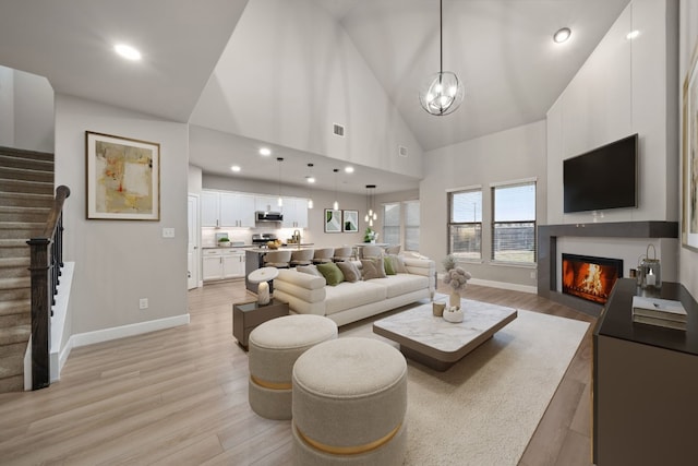 living room featuring a chandelier, high vaulted ceiling, and light hardwood / wood-style flooring