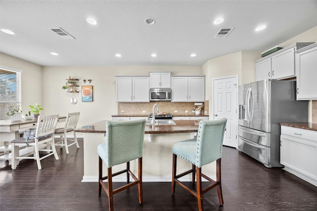 kitchen featuring white cabinets, dark hardwood / wood-style flooring, an island with sink, and appliances with stainless steel finishes