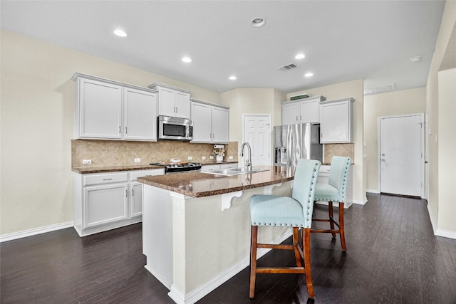 kitchen featuring white cabinets, dark wood-type flooring, an island with sink, and stainless steel appliances