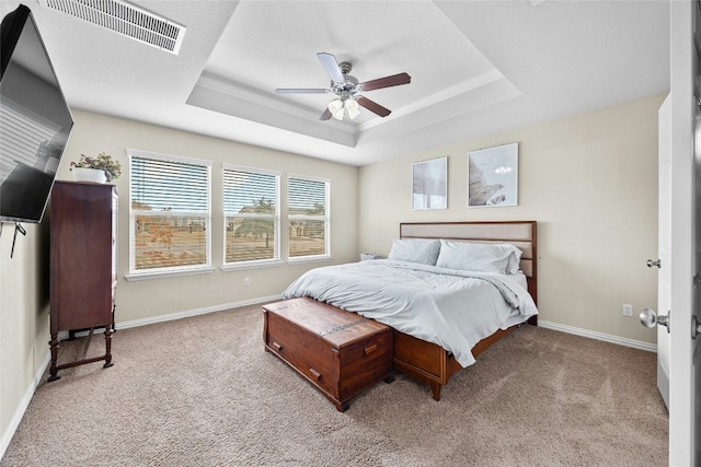 bedroom with light carpet, a tray ceiling, and ceiling fan