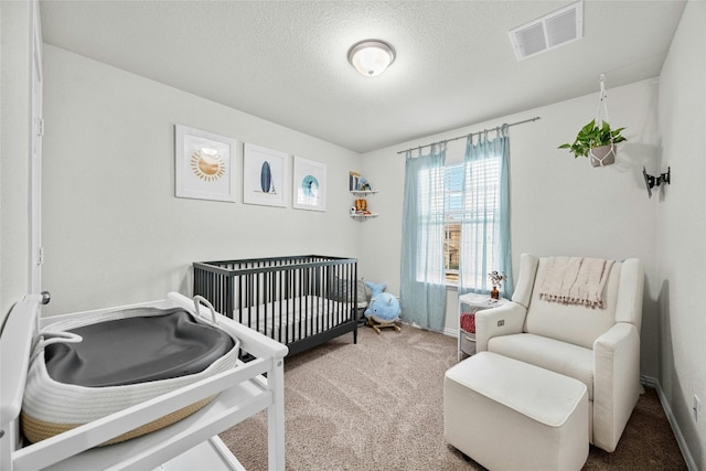 carpeted bedroom with a textured ceiling and a crib