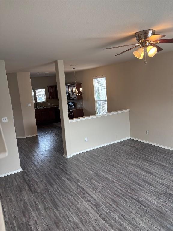 spare room with ceiling fan with notable chandelier and dark hardwood / wood-style floors