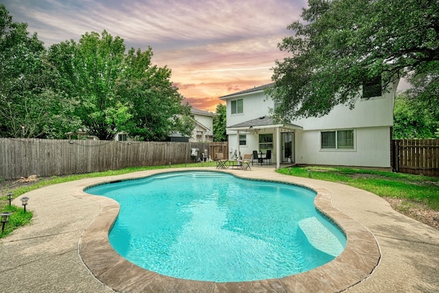 pool at dusk featuring a patio area