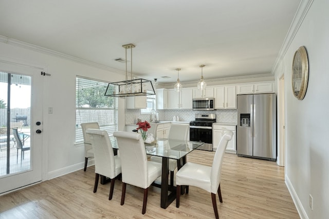 dining area with a wealth of natural light, crown molding, and light hardwood / wood-style floors