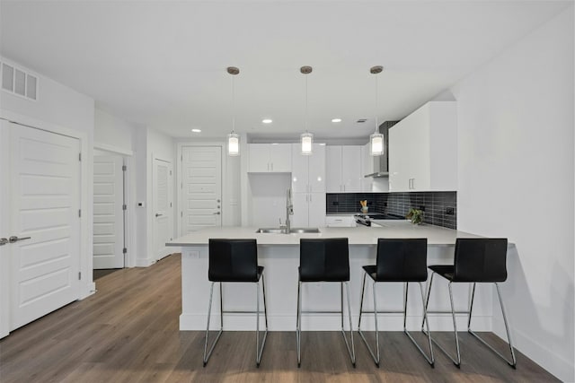 kitchen with decorative light fixtures, white cabinetry, kitchen peninsula, and sink