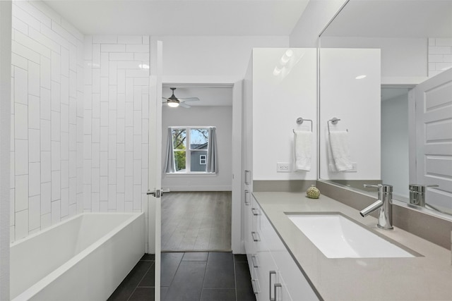 bathroom with tile patterned floors, ceiling fan, vanity, and tiled shower / bath