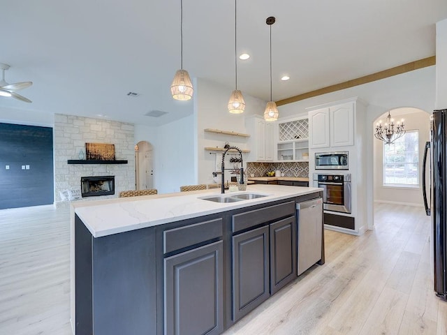 kitchen with white cabinets, appliances with stainless steel finishes, a kitchen island with sink, and pendant lighting