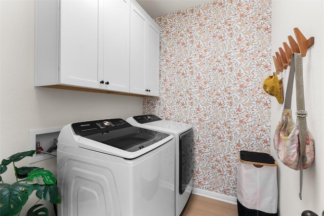 laundry area featuring cabinets, separate washer and dryer, and light hardwood / wood-style floors