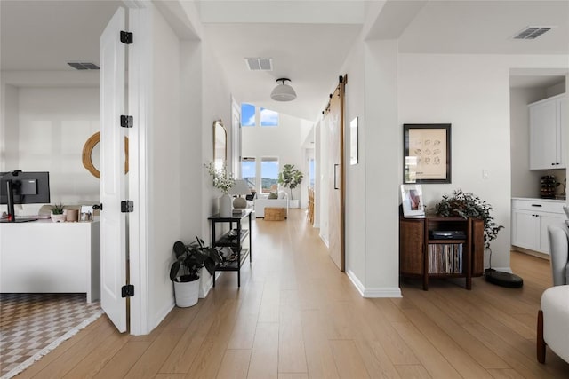 corridor with a barn door and light wood-type flooring