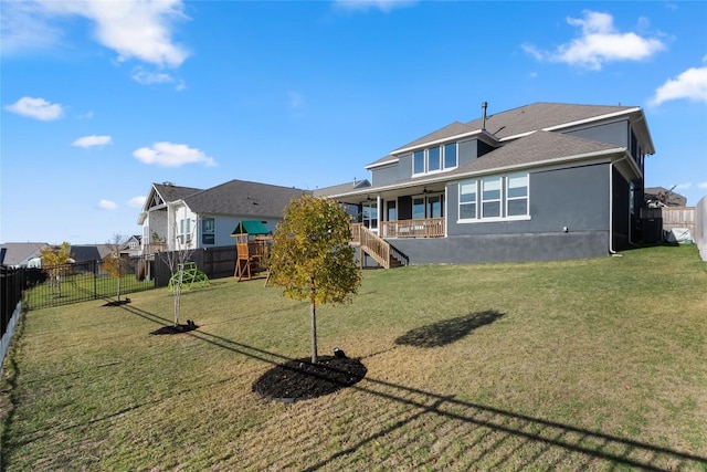 back of house featuring a lawn and a playground