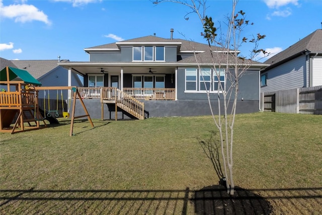 back of house featuring ceiling fan, a lawn, and a playground