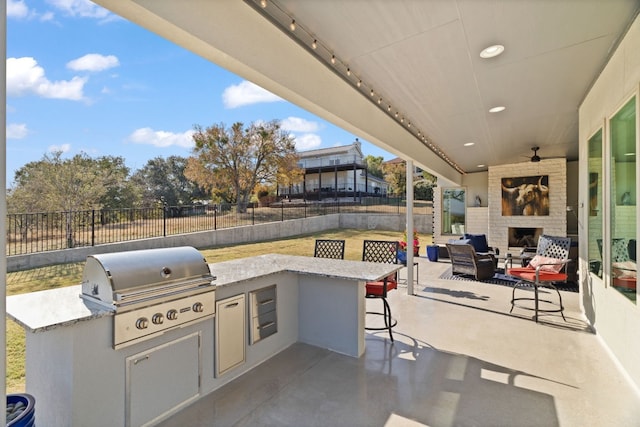 view of patio / terrace featuring area for grilling, exterior bar, exterior fireplace, ceiling fan, and grilling area