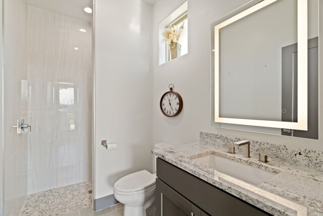 bathroom with tile patterned flooring, toilet, vanity, and tiled shower