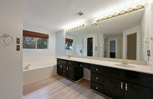 full bathroom with double vanity, visible vents, a sink, and wood finished floors