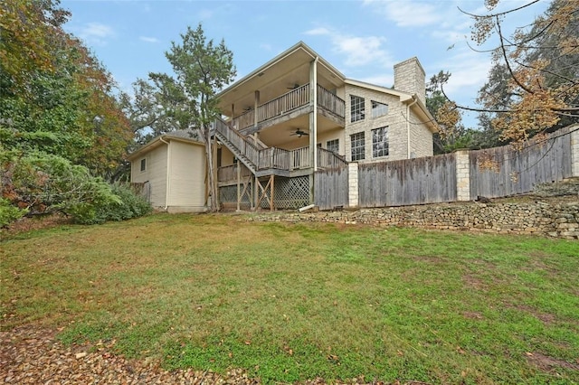 rear view of property featuring a lawn, a ceiling fan, a chimney, stairway, and fence