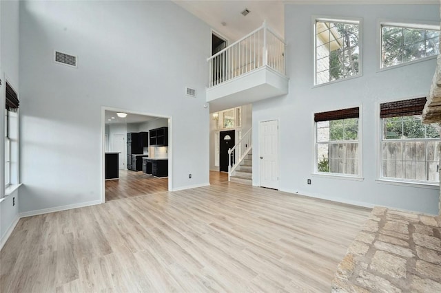 unfurnished living room with visible vents, stairway, and wood finished floors