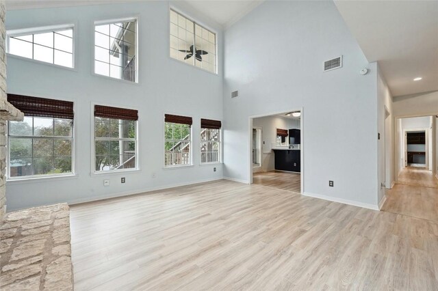 unfurnished living room featuring light wood-type flooring, visible vents, and baseboards