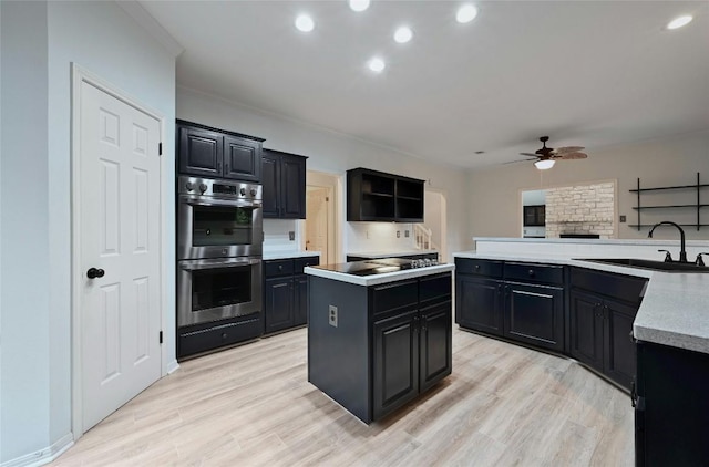 kitchen featuring a sink, dark cabinetry, stainless steel double oven, and a center island