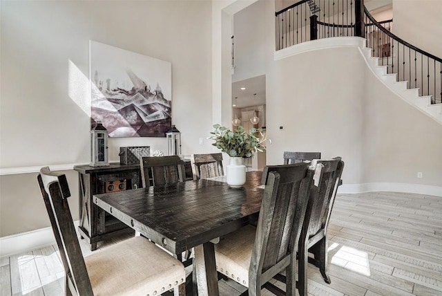 dining space featuring a towering ceiling and light wood-type flooring