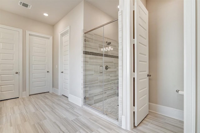 bathroom featuring hardwood / wood-style floors and a shower with shower door