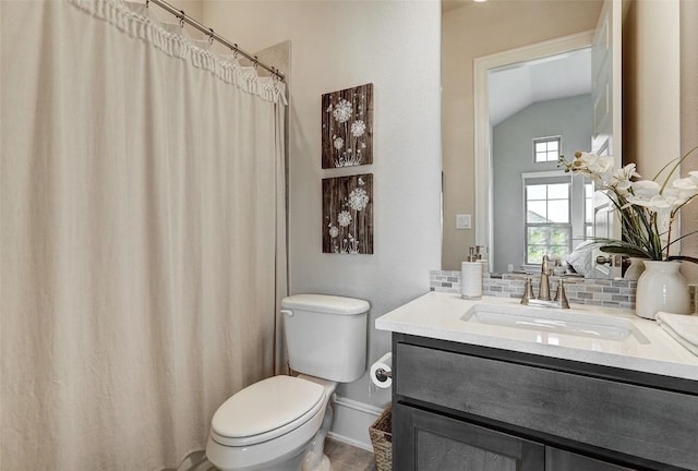 bathroom with vanity, tile patterned floors, vaulted ceiling, toilet, and tasteful backsplash