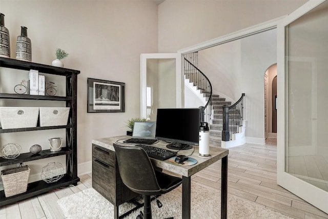 office featuring french doors, light hardwood / wood-style flooring, and a high ceiling