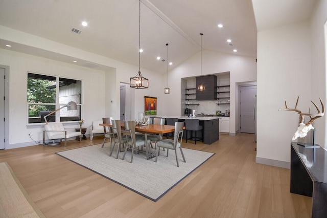 dining space with light hardwood / wood-style flooring and high vaulted ceiling