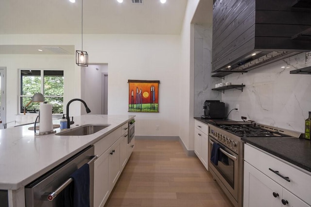 kitchen featuring sink, decorative backsplash, decorative light fixtures, light hardwood / wood-style floors, and stainless steel appliances