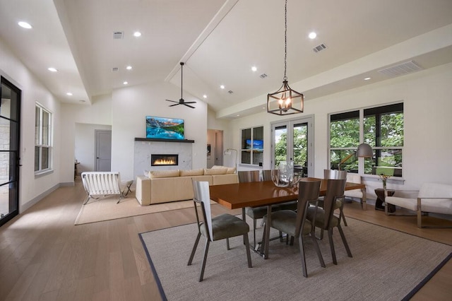 dining room with ceiling fan, wood-type flooring, and high vaulted ceiling