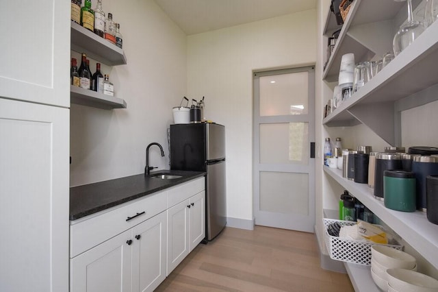 interior space featuring white cabinets, stainless steel fridge, light hardwood / wood-style flooring, and sink