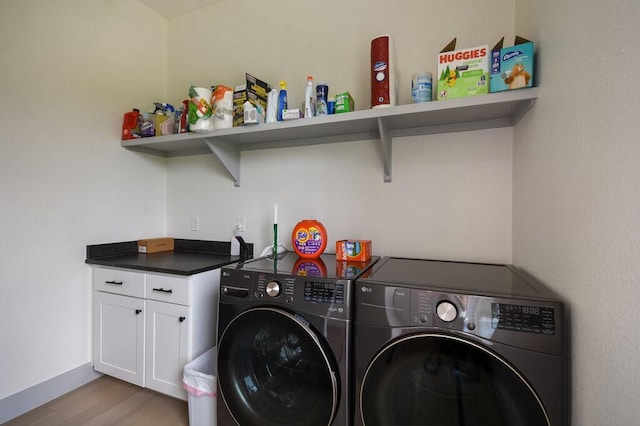 clothes washing area featuring washer and clothes dryer, cabinets, and light wood-type flooring