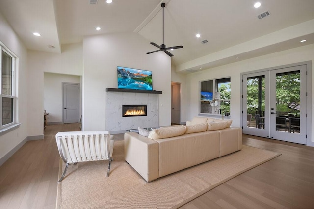 living room with ceiling fan, light hardwood / wood-style floors, high vaulted ceiling, and french doors