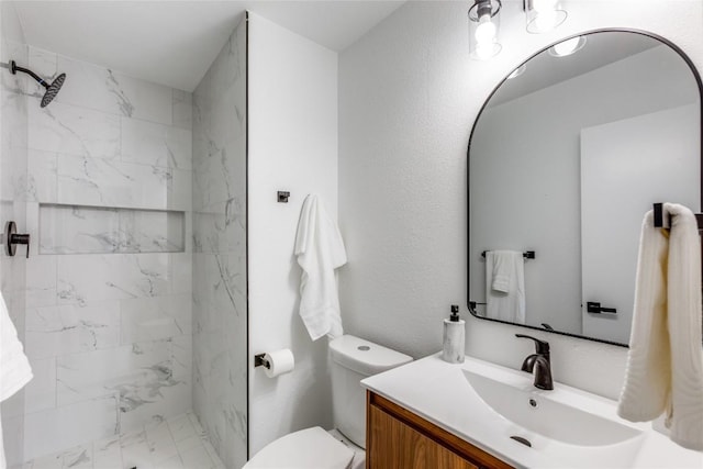 bathroom with vanity, toilet, and a tile shower