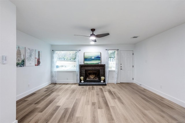 unfurnished living room with ceiling fan, light hardwood / wood-style floors, and a brick fireplace