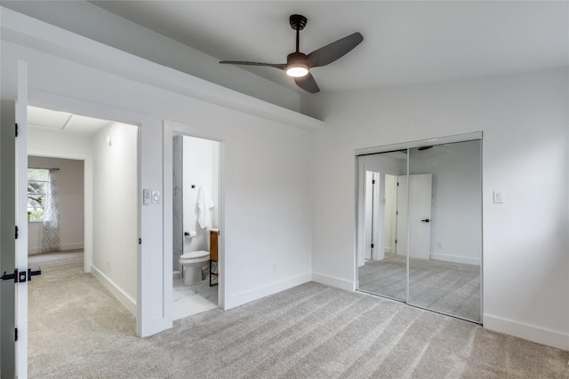 unfurnished bedroom with ensuite bathroom, lofted ceiling, ceiling fan, light carpet, and a closet