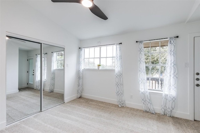 unfurnished bedroom featuring ceiling fan, light colored carpet, vaulted ceiling, and a closet