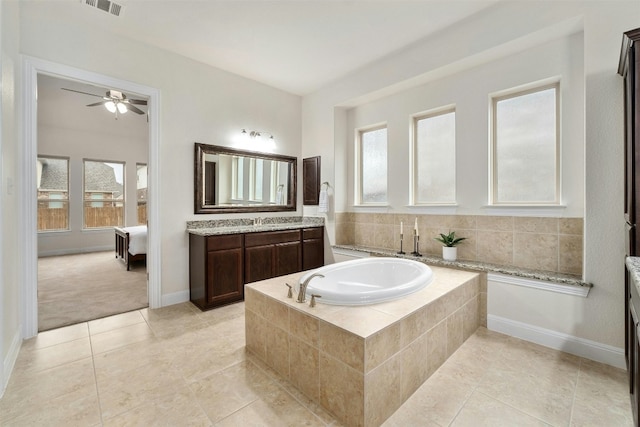 bathroom with tile patterned floors, ceiling fan, vanity, and a relaxing tiled tub