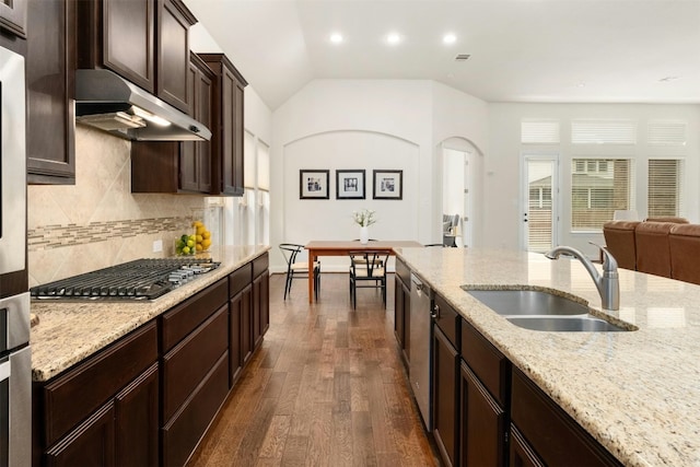 kitchen featuring dark wood-type flooring, sink, vaulted ceiling, light stone countertops, and appliances with stainless steel finishes