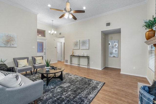 living room with ceiling fan with notable chandelier, wood-type flooring, a textured ceiling, and ornamental molding