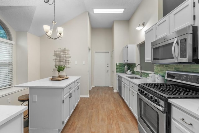 kitchen featuring sink, an inviting chandelier, decorative light fixtures, white cabinets, and appliances with stainless steel finishes