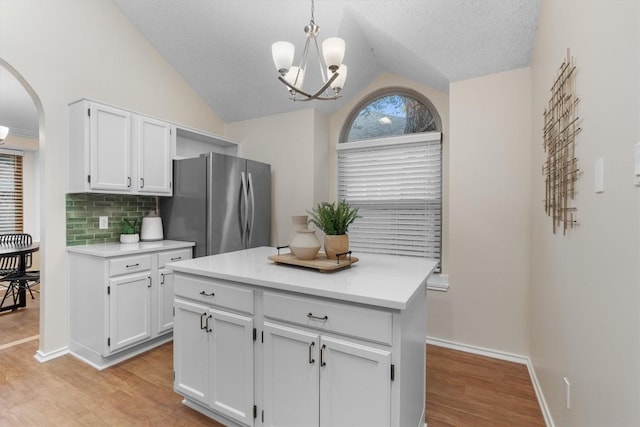 kitchen featuring lofted ceiling, white cabinets, stainless steel fridge, decorative light fixtures, and light hardwood / wood-style floors