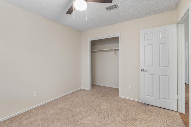 unfurnished bedroom with light carpet, a textured ceiling, a closet, and ceiling fan