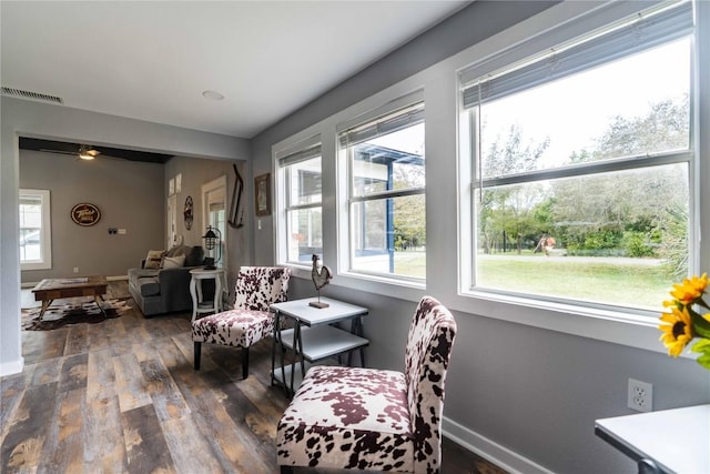 sitting room with ceiling fan and dark wood-type flooring