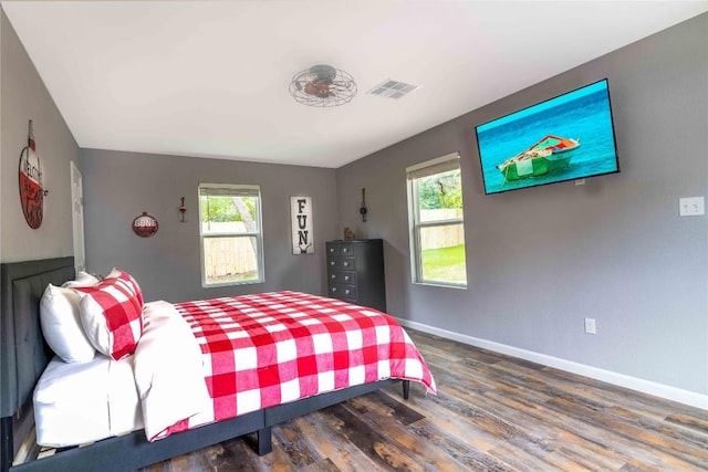 bedroom with multiple windows and dark wood-type flooring