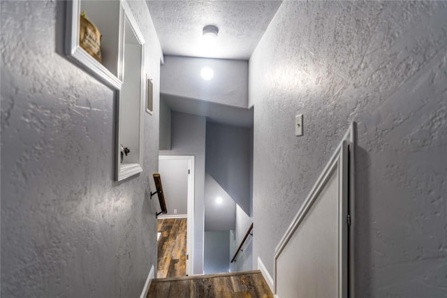 stairs featuring hardwood / wood-style floors and a textured ceiling